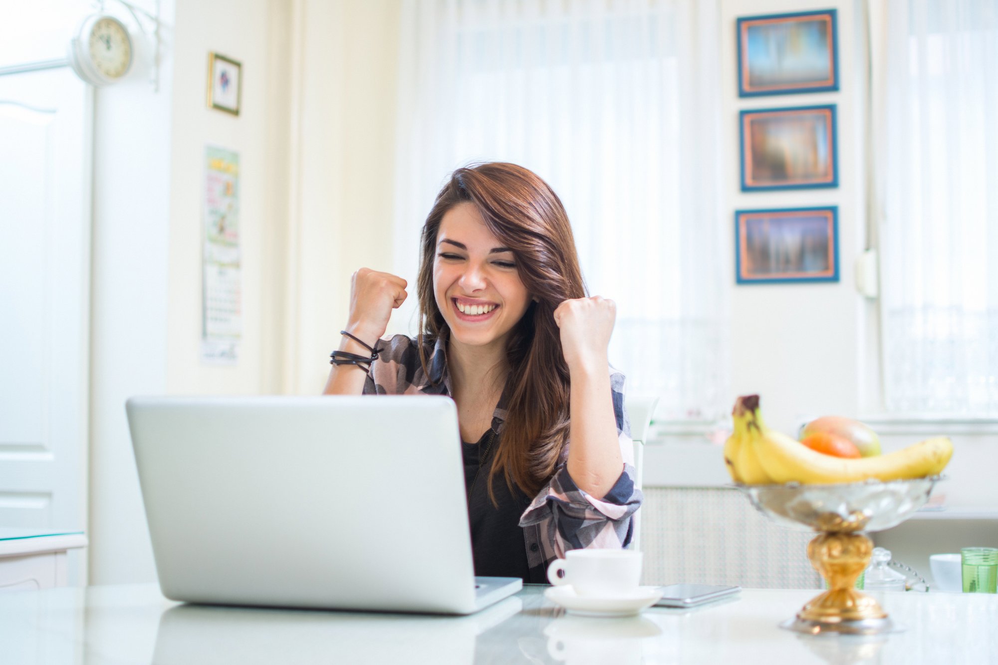 Portrait-of-happy-young-woman-celebrating-success-with-arms-up-in-front-of-laptop-at-home.-885515492_2125x1416
